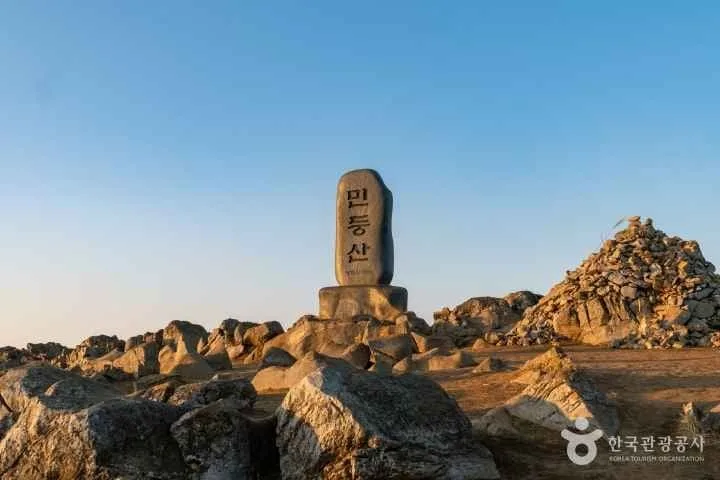 여러-바위와-돌-사이에-민둥산-정상석이-서있다.