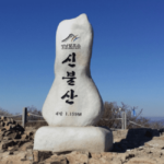 푸른-하늘-배경으로-신불산-정상석이-보여지고-있다.