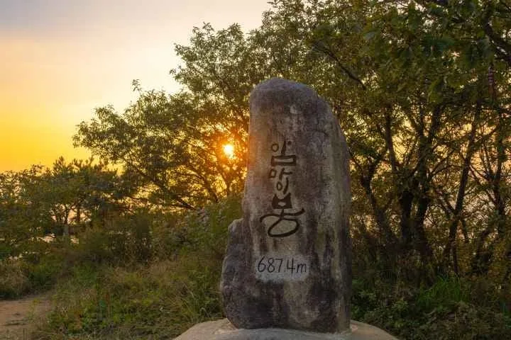 암마이봉-정상석-뒤로-노을이-비친다.