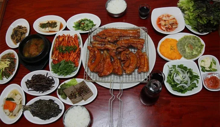 고추장-약돌-삼겹살구이-및-밑반찬이-가득-놓여있다.