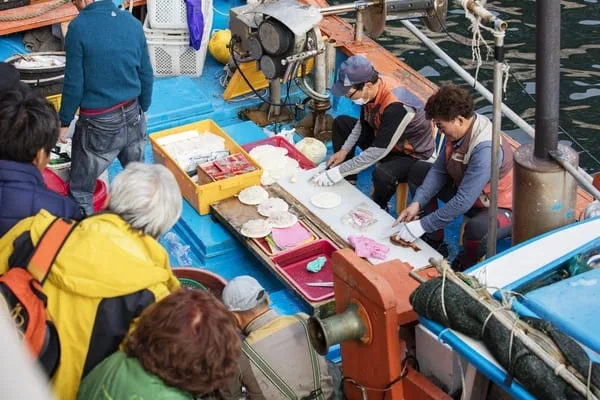 두-사람이-배-위에서-해산물을-손질하고-있다.