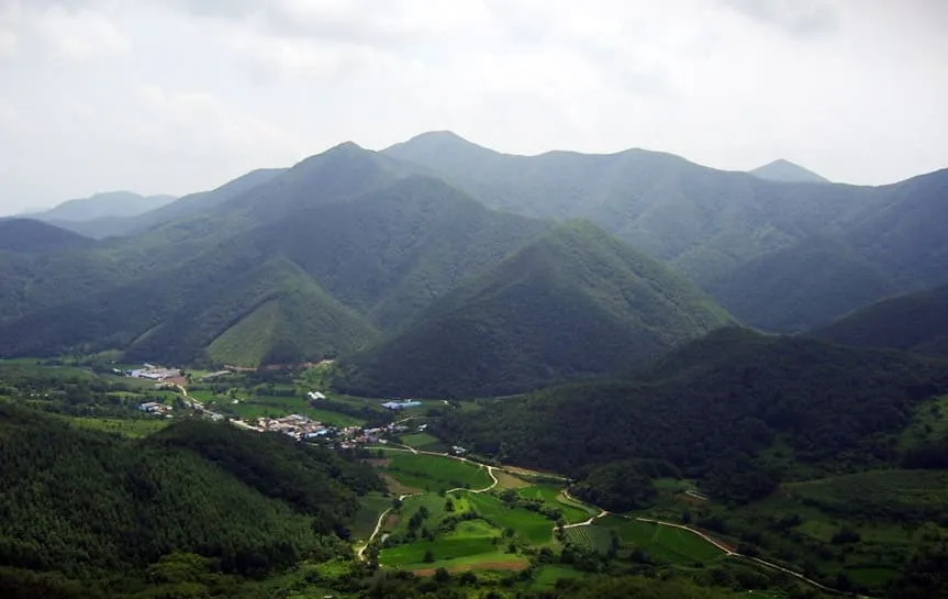 솟아있는-여러-산과-그-아래-농가-마을의-풍경